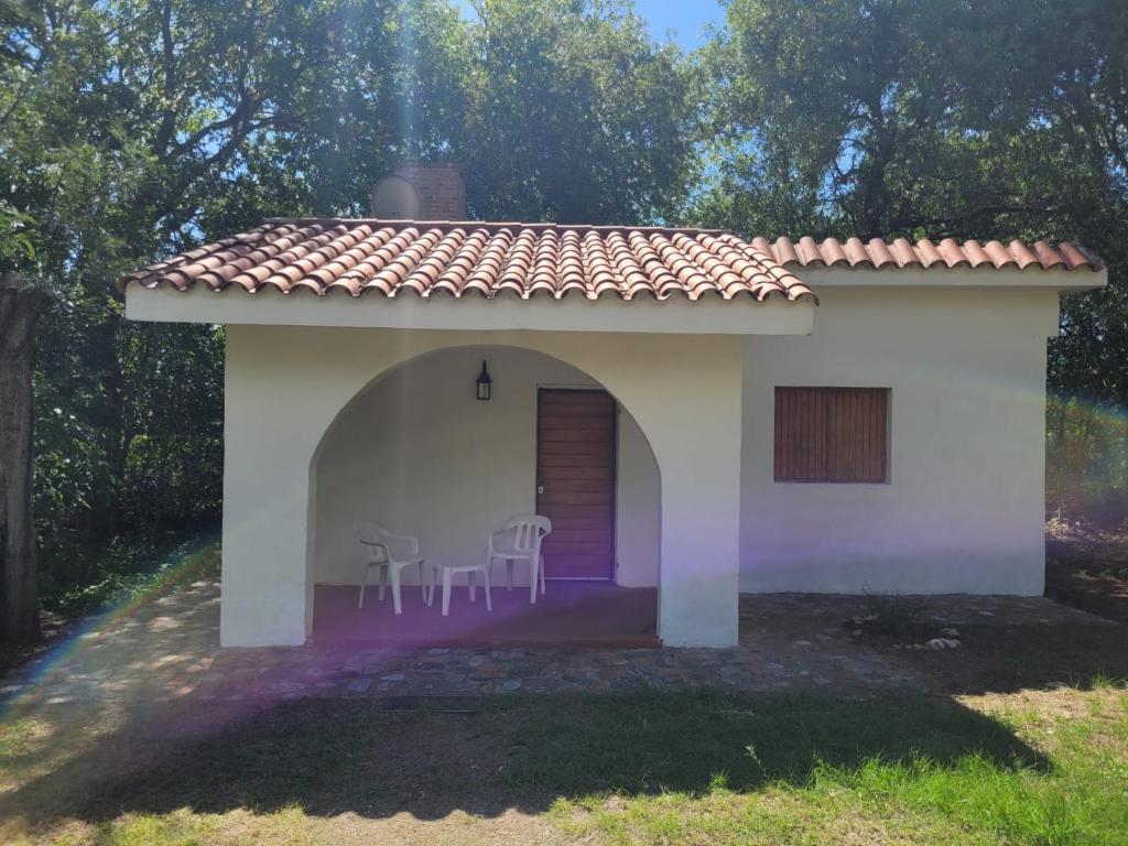 ein kleines weißes Haus mit Stühlen davor in der Unterkunft Don Juan M Cabañas in Villa Las Rosas