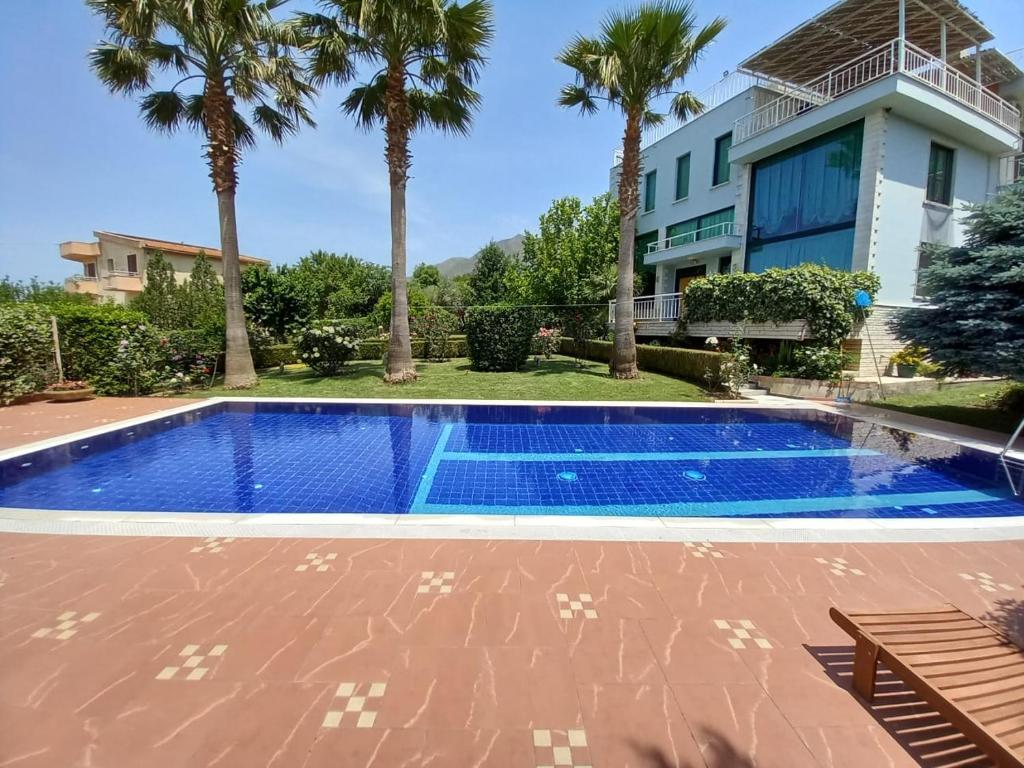 a swimming pool in front of a house with palm trees at Family Beach Swimming Pool Villa Luanit in Tragjas