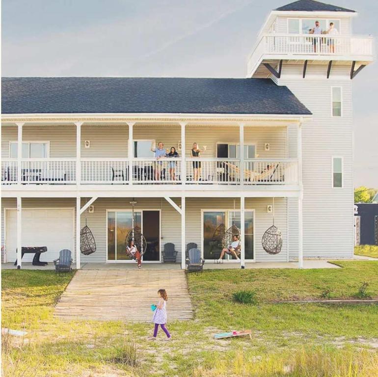 a little girl walking in front of a large house at Sojourn The Lighthouse Beach Front Resort Villa in North Camellia Acres