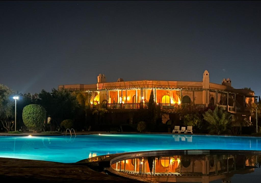 un grande edificio con piscina di notte di Palmeraie 5 Vue Piscine et Jardin a Marrakech
