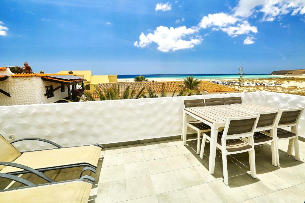 Un patio con mesa y sillas y la playa. en Villa Sotavento Ocean Views Modern New Apartment in Natural Park, en Playa de Jandía