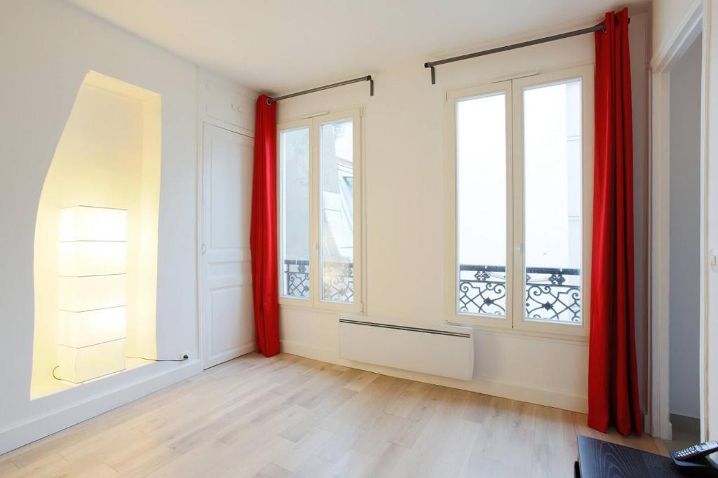 une pièce vide avec des rideaux rouges et 2 fenêtres dans l'établissement Lovely apartment 10 min walk to Louvre 3 Persons, à Paris