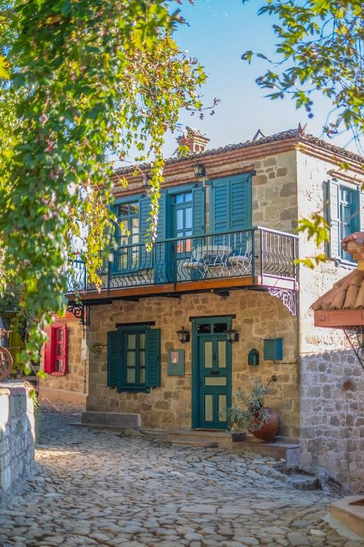 an old house with green shutters and a balcony at Orion Adatepe in Adatepe