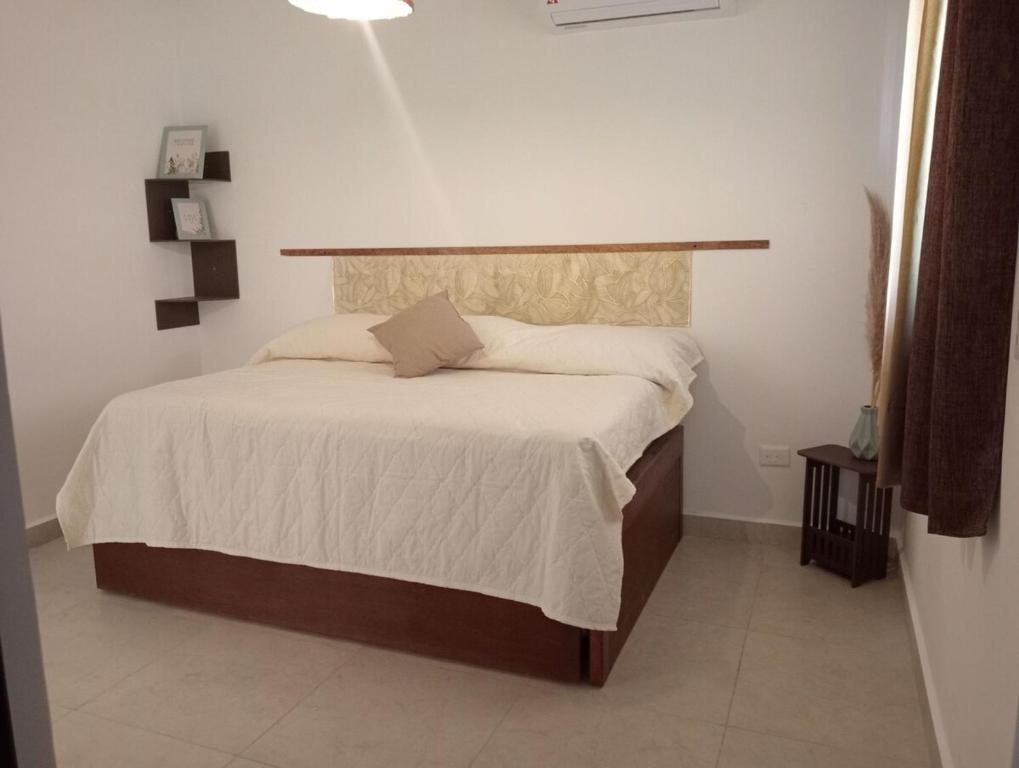 Un dormitorio con una cama grande con sábanas blancas. en Departamento Relax, en Mazatlán