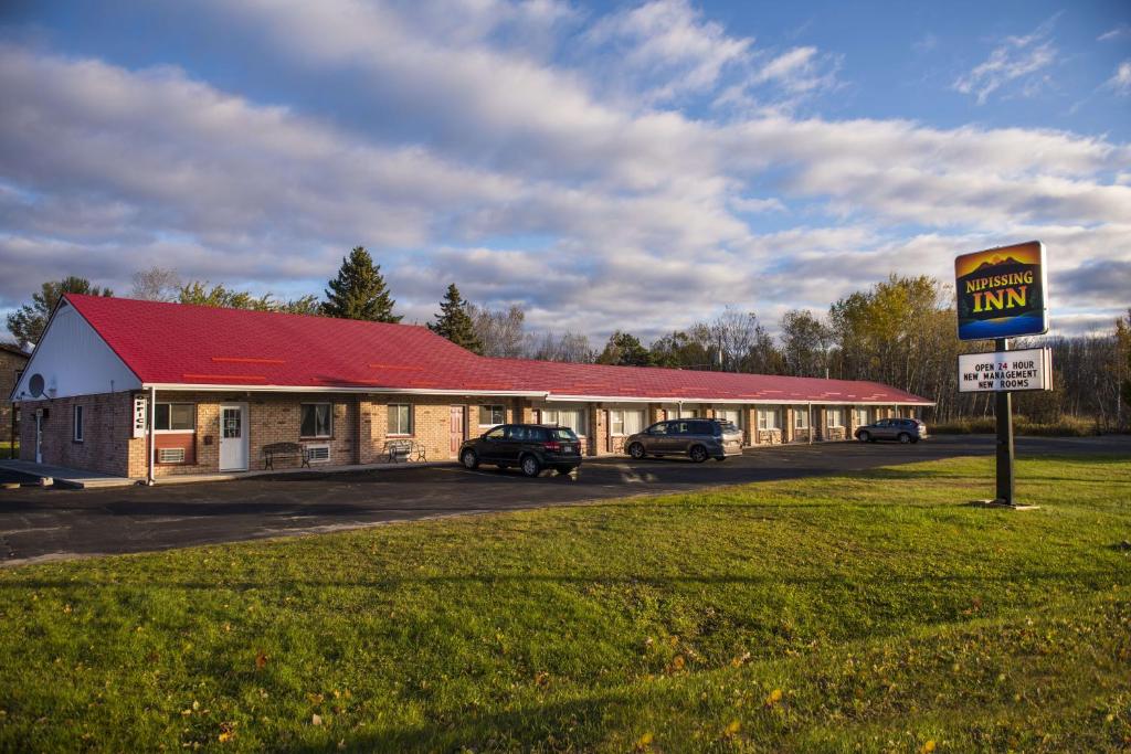 ein Motel mit Autos, die vor einem Gebäude geparkt sind in der Unterkunft Nipissing Inn in North Bay