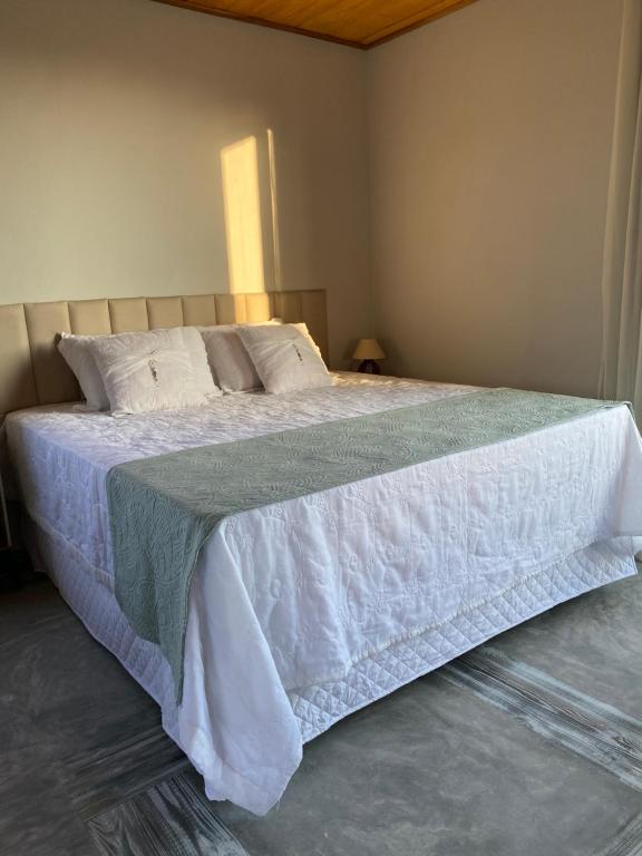 a bedroom with a bed with a white comforter at Chalé Frutas Especiais in Mucugê