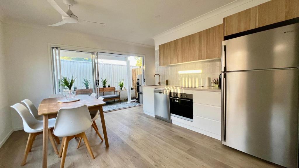 a kitchen with a table and a stainless steel refrigerator at Coastal Escape Watch Horses Pass Walk to Beach in Redcliffe