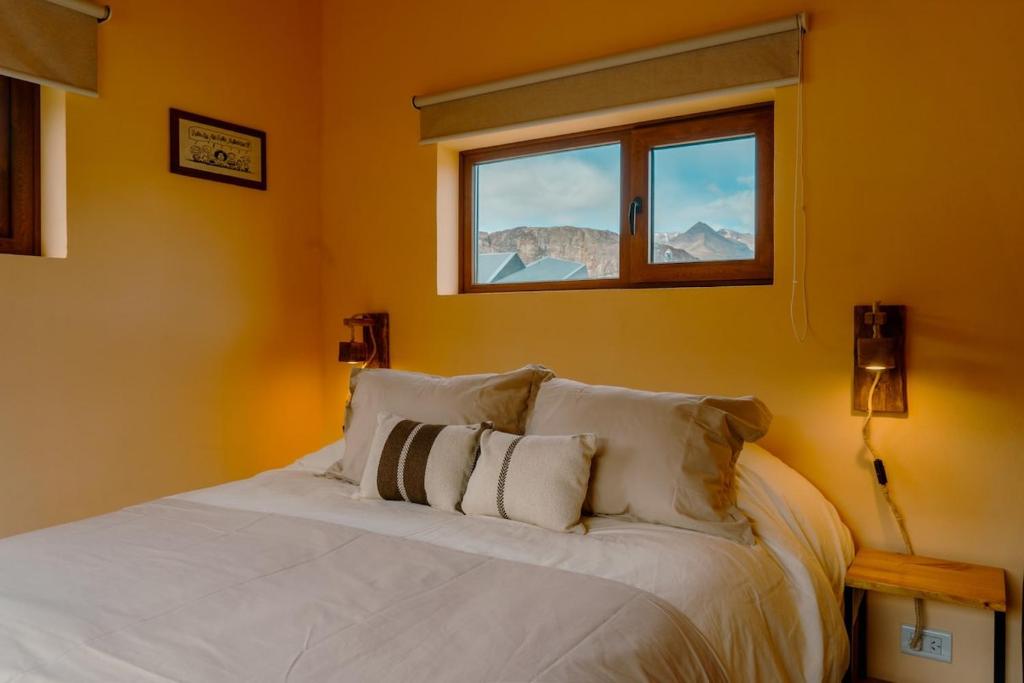 een slaapkamer met een wit bed met een raam bij Berberis Apart in El Chalten