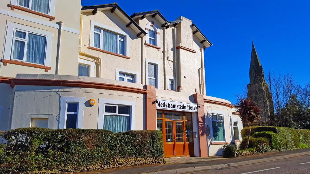 a building on a street with a church in the background at Medehamstede Hotel in Shanklin