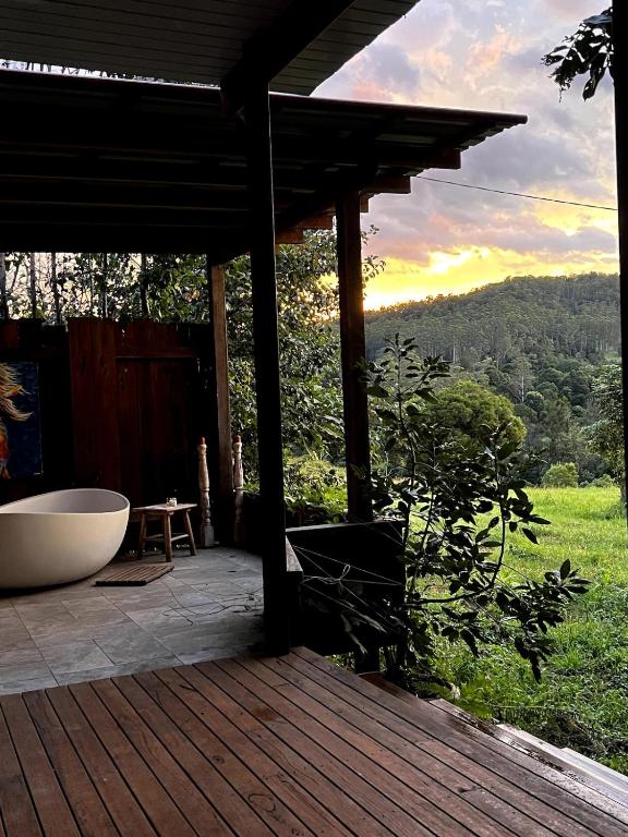 a wooden deck with a bath tub and a table at Oma’s Kitchen at Creegans Cottage in Barkers Vale