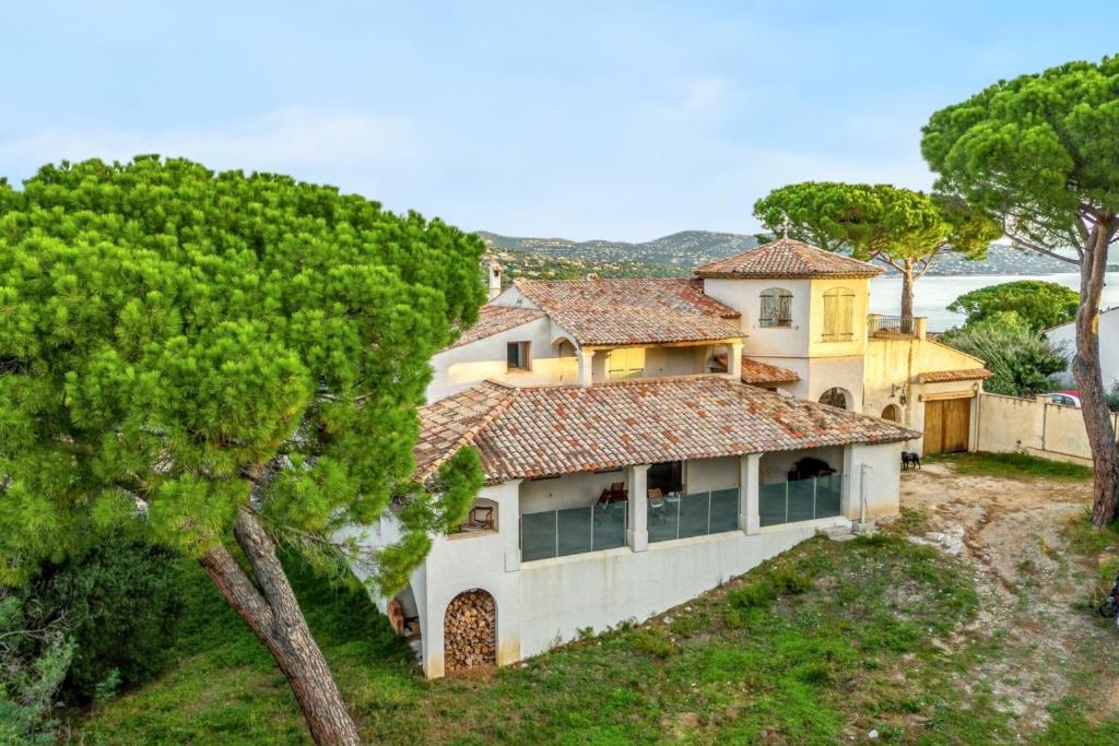 une grande maison blanche sur une colline avec des arbres dans l'établissement Maison élégante à Sainte-Maxime avec vue sur la mer, à Sainte-Maxime