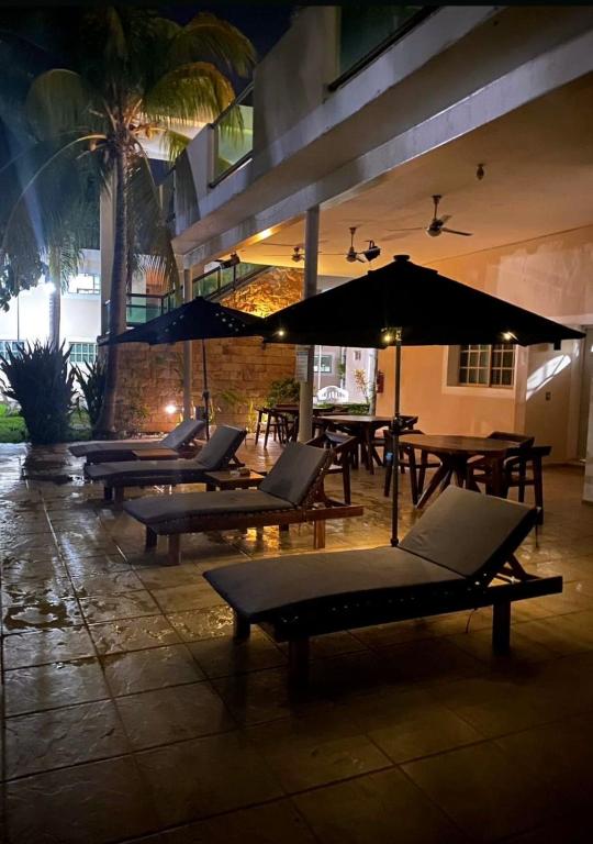 a group of lounge chairs and tables with umbrellas at Villas Paraíso in Mérida