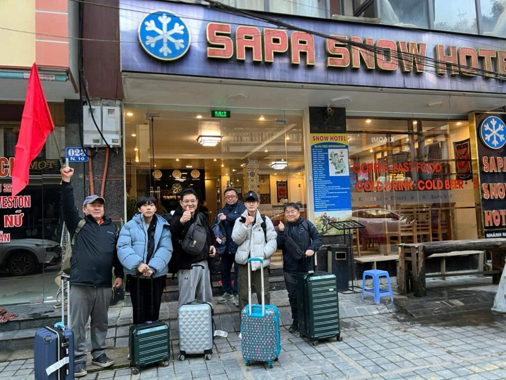 a group of people standing in front of a store with luggage at Sapa Snow Hotel in Sa Pa
