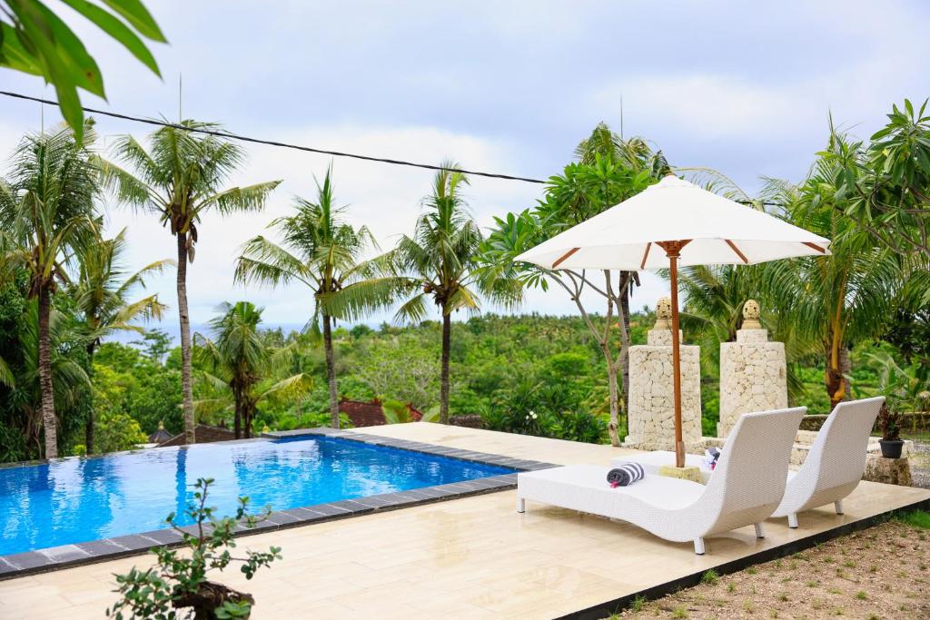 a villa with a swimming pool and palm trees at Mahendra Cottage in Nusa Penida