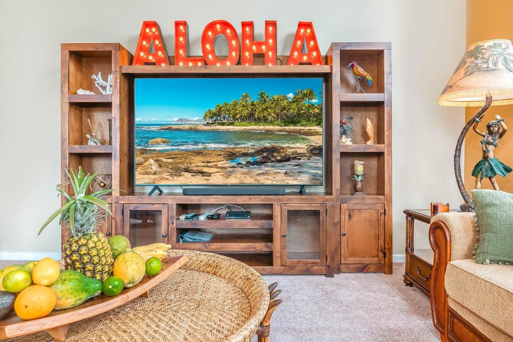 Una sala de estar con televisión y una mesa con frutas. en Hilton Pool Pass included - Luxury Waikoloa Retreat - 3BR, en Waikoloa
