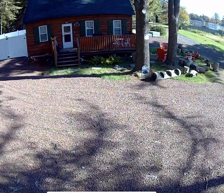 uma cabana de madeira com um alpendre e uma árvore em The Rustic Cabin em Blakeslee