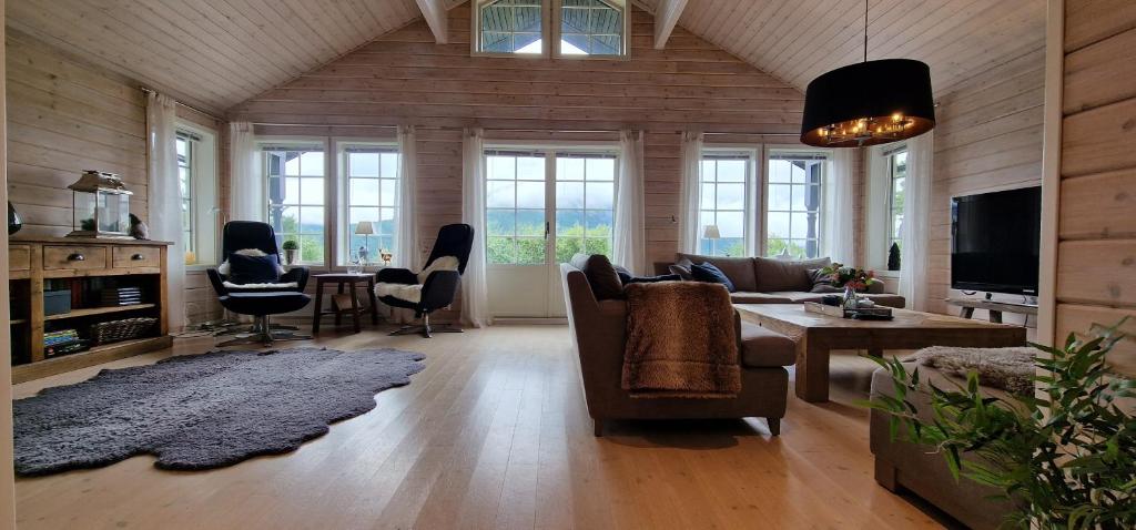 een woonkamer met een bank, een tafel en stoelen bij Panorama Cabin - Stunning Mountain Views and Outdoor Jacuzzi Option in Bjorli