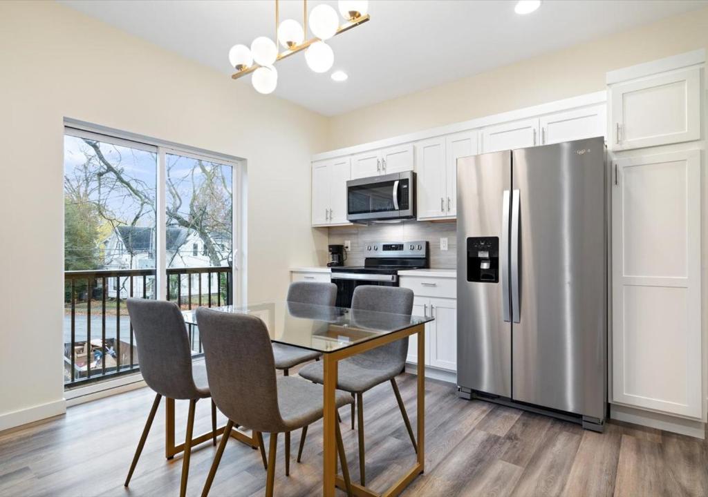 Una cocina con una mesa y un refrigerador de acero inoxidable. en Fall at Golden Goose including King Bed, Parking, Security and Laundry, en Evansville