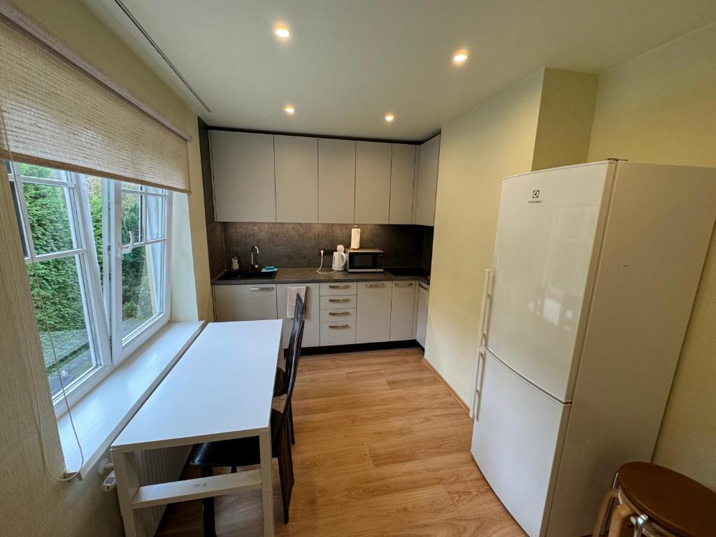 a kitchen with a table and a white refrigerator at Sunny 2BR with Balcony - 70m2 - 200m Beach in Jūrmala