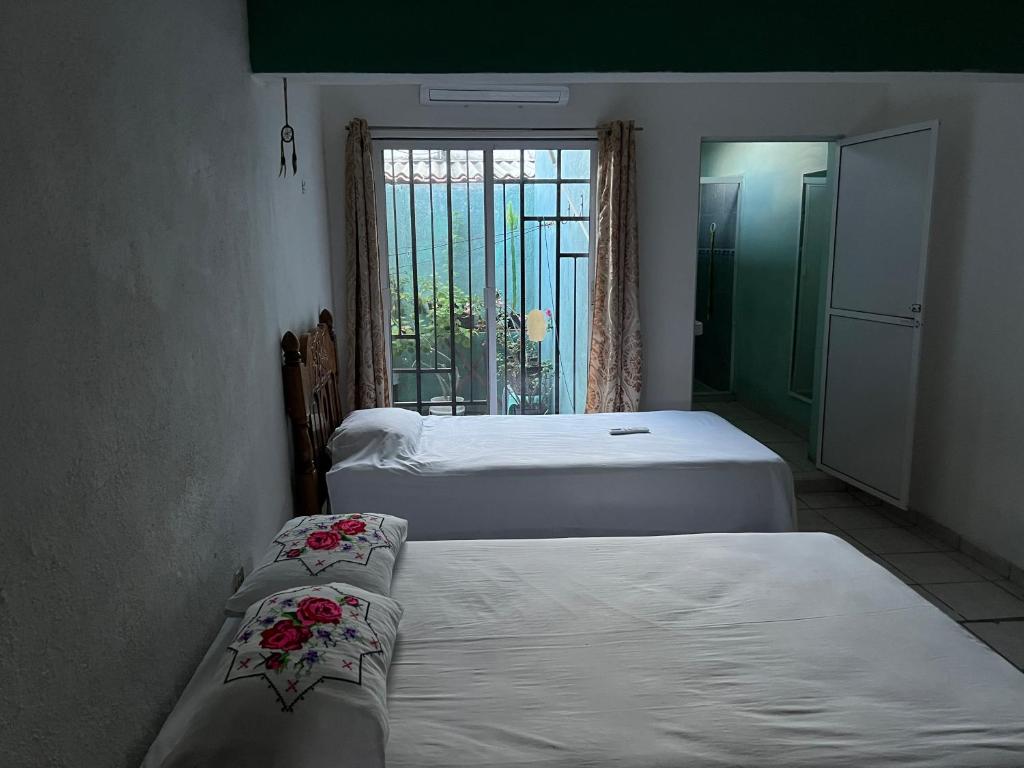 two beds in a small room with a window at Casa Arboledas in Manzanillo