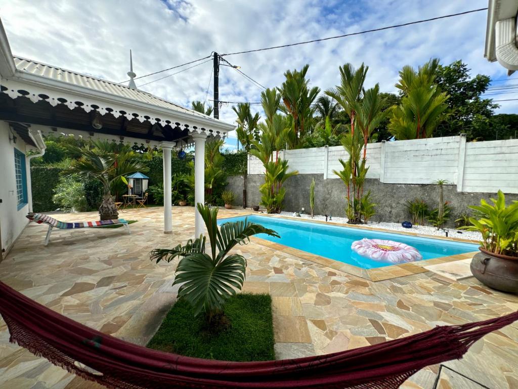eine Hängematte vor einem Haus mit einem Pool in der Unterkunft Cottage Palmier Rouge in La Trinité