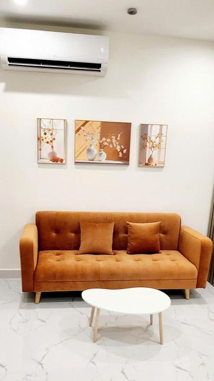 ein Wohnzimmer mit einem braunen Sofa und einem weißen Tisch in der Unterkunft Glory Heights - Vinhomes Grank Park in Long Bình