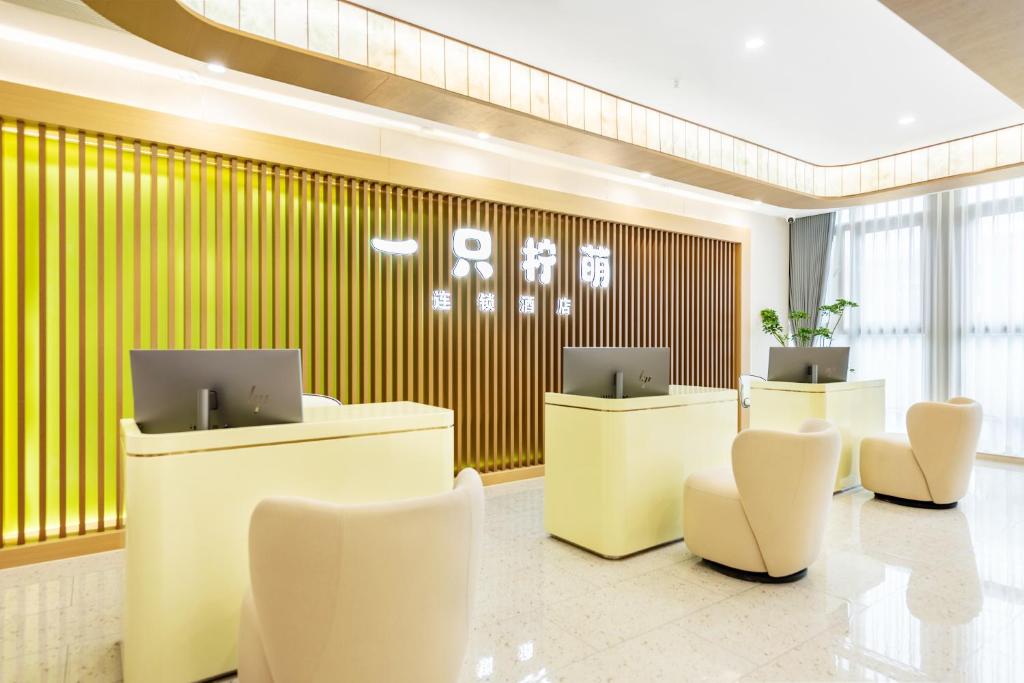 杭州一只柠萌酒店(湖滨步行街凤起路地铁站店)的大堂设有2张办公桌和白色椅子。