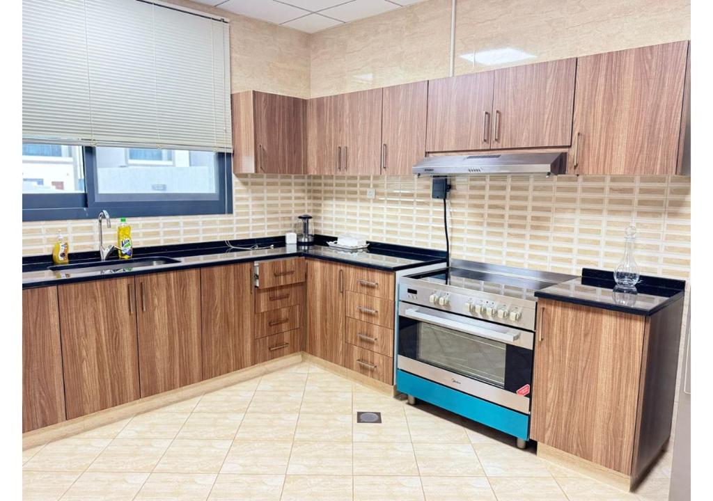 a kitchen with wooden cabinets and a stove top oven at 1 - BLUE WORLD - Al Dana Villas in Fujairah