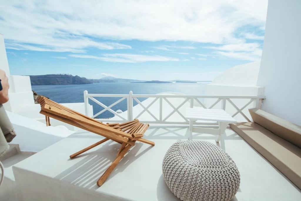 a chair on a balcony with a view of the water at Blu Bianco Cave House by SV in Oia