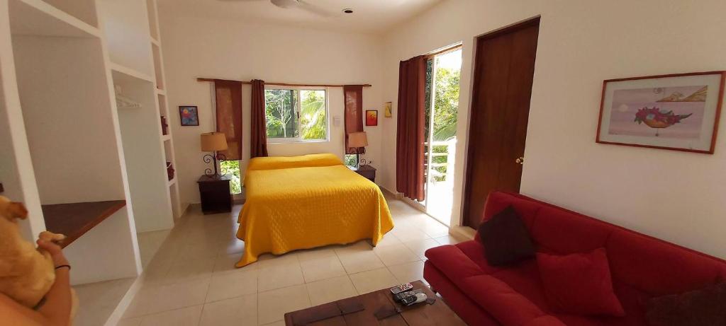 Mini Pini Birdwatching and cenote loft4 you only في كوزوميل: غرفة معيشة مع سرير وأريكة حمراء