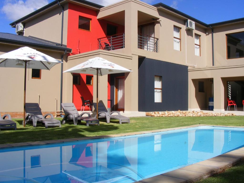 a house with a swimming pool in front of a house at Karoo Sun Boutique Guest House in Oudtshoorn