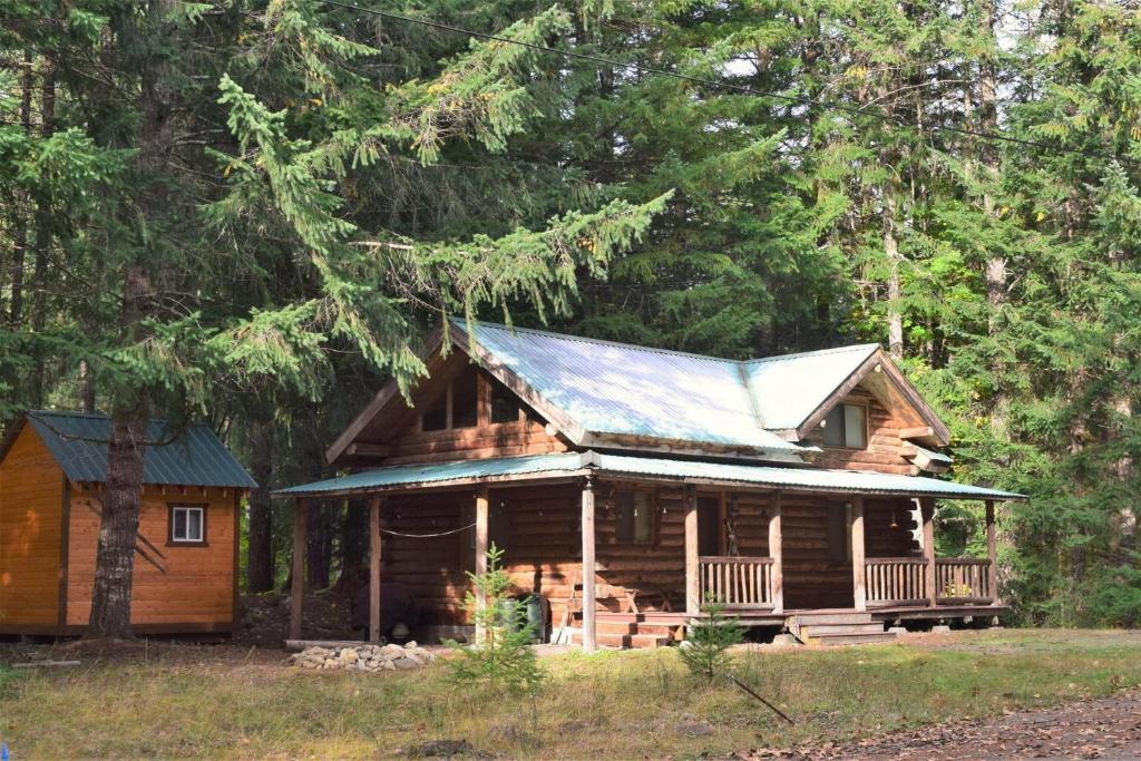 a log cabin in the woods with a tin roof at Cascade Log Cabin | Mt Rainier, WIFI, Log Cabin in Packwood