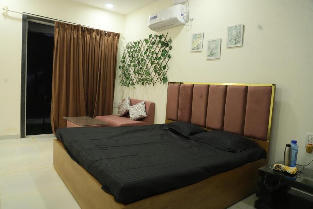 a bedroom with a large bed and a chair at Ivy Bliss Studio with Common Pool, B 14, Karjat in Karjat