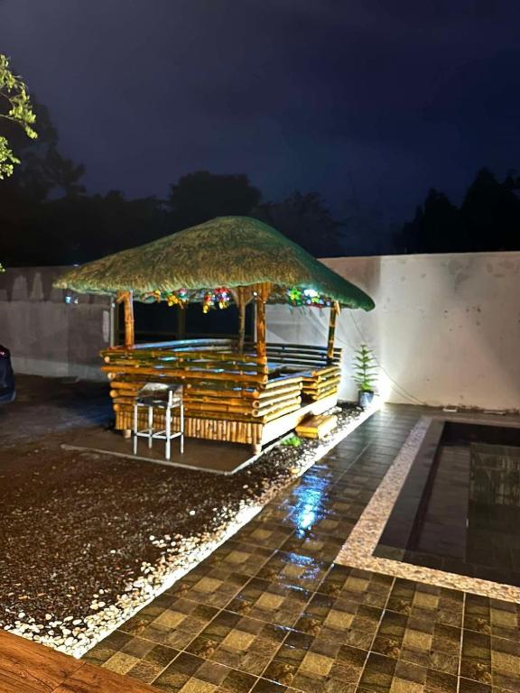 a gazebo with a grass roof at night at Styacation in Sariaya