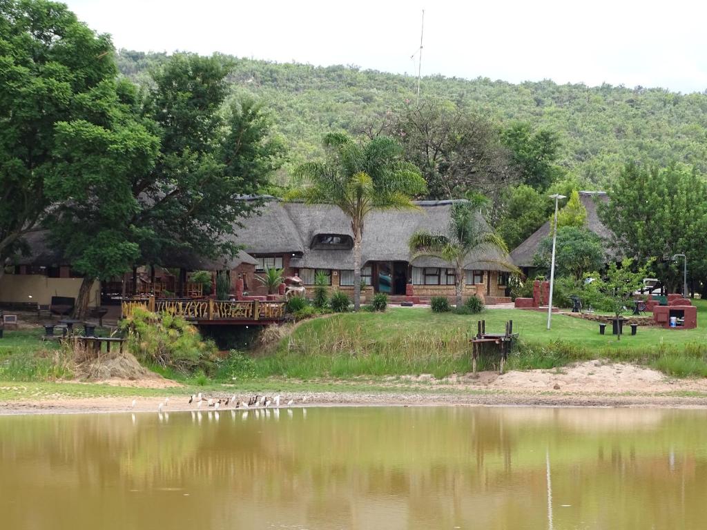 a house next to a lake with ducks in the water at Abba Game Lodge in Modimolle