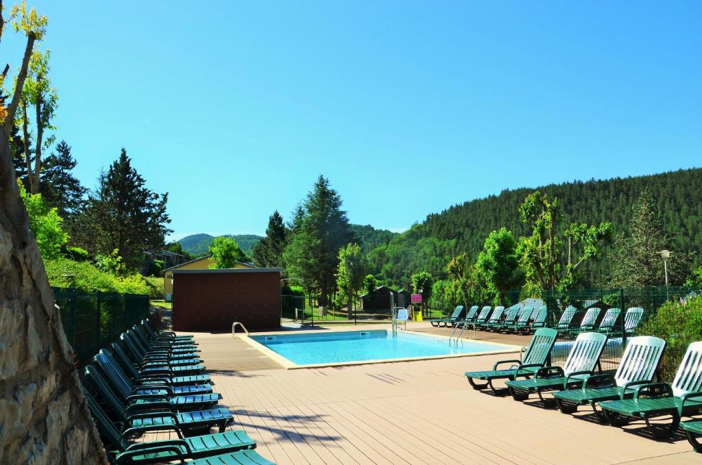 a row of lawn chairs next to a swimming pool at Domaine Aigoual Cevennes in Meyrueis