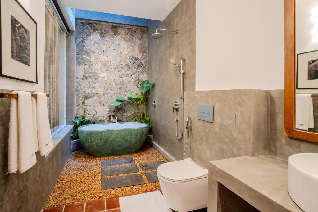 a bathroom with a tub and a toilet and a sink at Aurora in Unawatuna