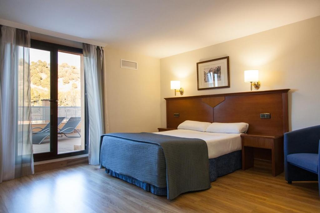 a hotel room with a bed, chair and a television at Porcel Alixares in Granada