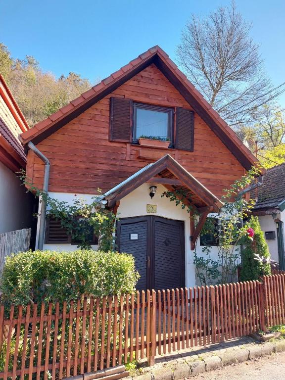 a house with a wooden fence in front of it at Garden Cottage Zebegény in Zebegény