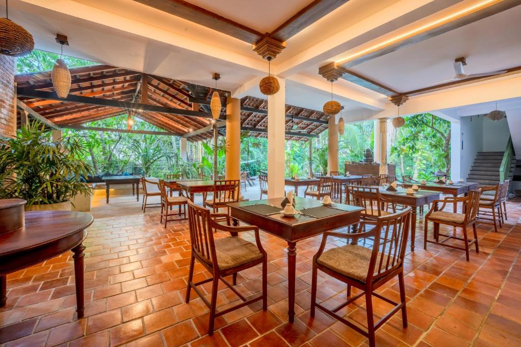 a restaurant with wooden tables and chairs and large windows at Aurora in Unawatuna