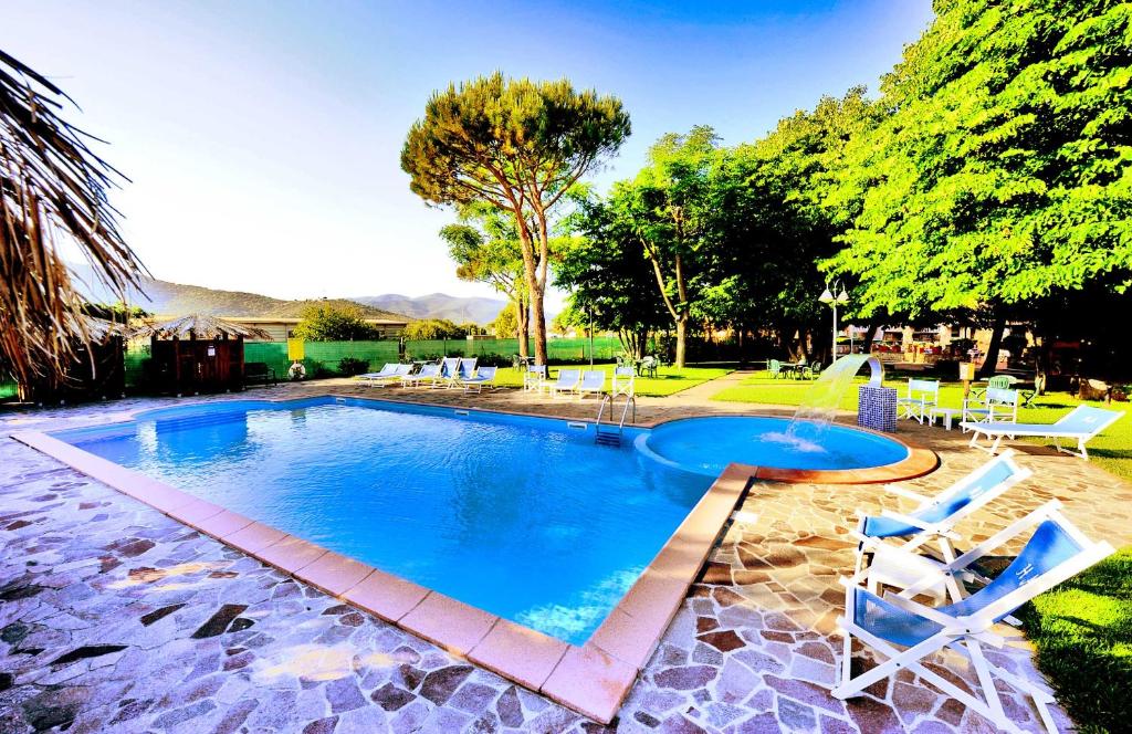 a swimming pool with two chairs and a table at Hotel Anfora in Castiglione della Pescaia