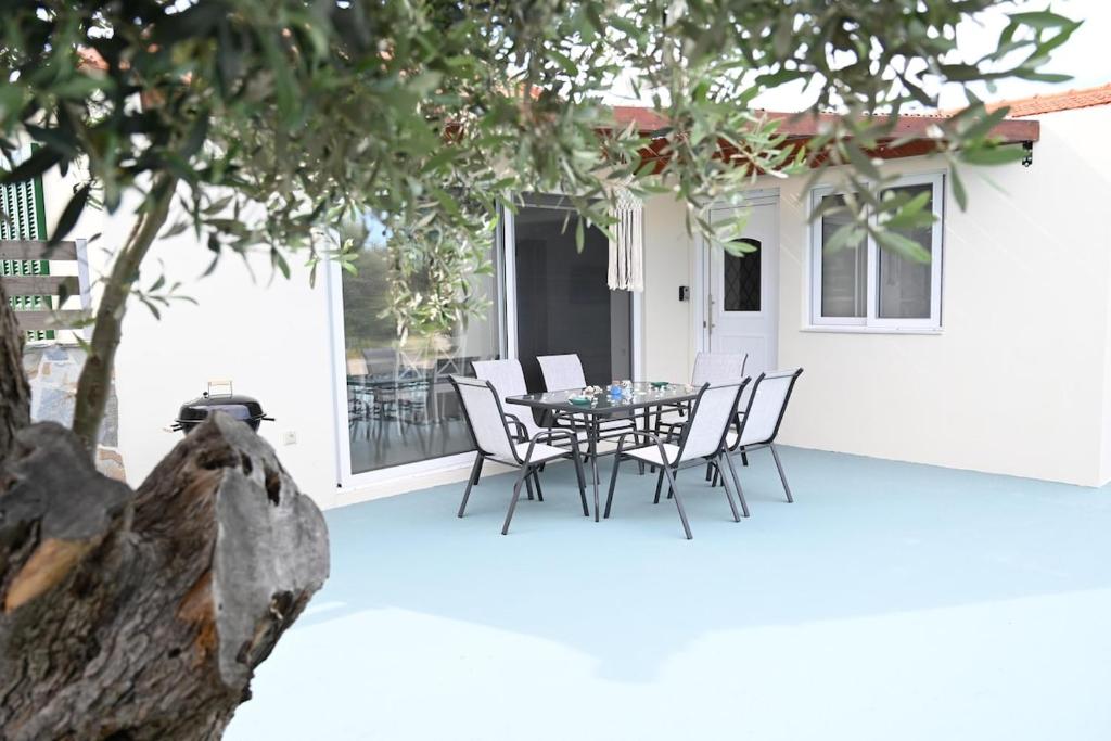 a patio with a table and chairs and a tree at Myrteni guesthouse in Ialysos