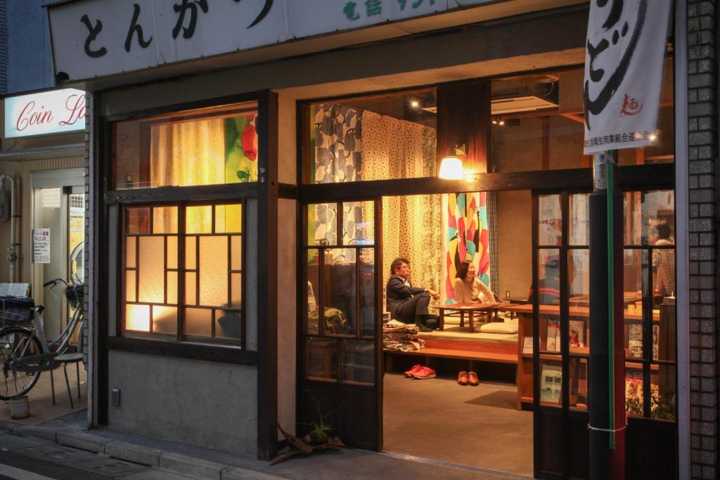 a store front with a man sitting in the window at Sheena To Ippei in Tokyo