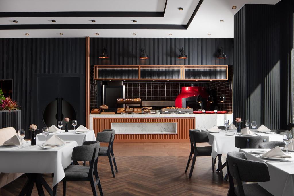 a restaurant with white tables and chairs and a kitchen at Delta Hotels by Marriott Istanbul Vadi in Istanbul