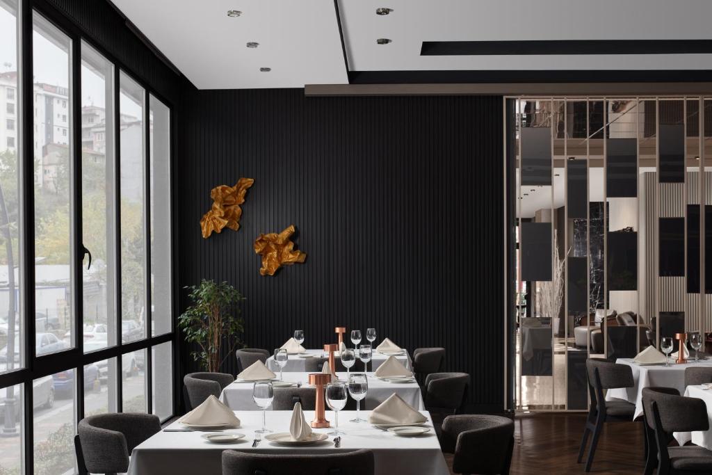 a restaurant with white tables and chairs and windows at Delta Hotels by Marriott Istanbul Vadi in Istanbul
