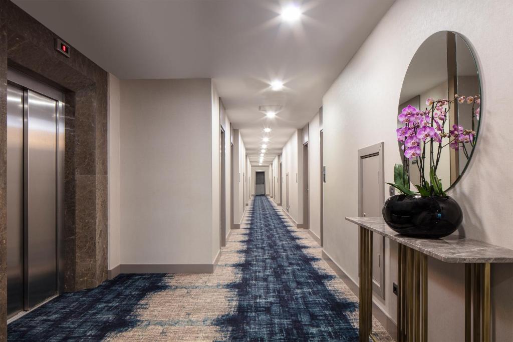 a long hallway with a mirror and flowers in a vase at Delta Hotels by Marriott Istanbul Vadi in Istanbul