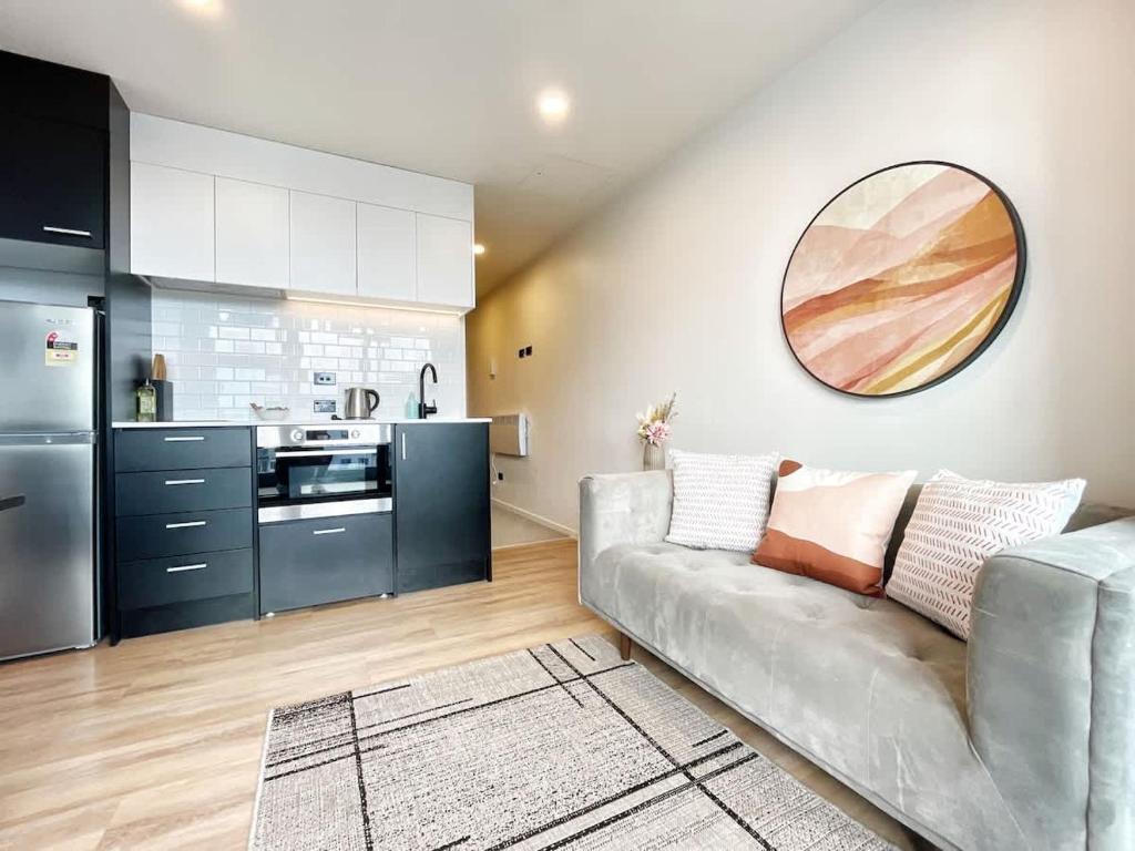 a living room with a couch and a kitchen at Chic Downtown 1Bed Aircon Apt with Pool Gym Sauna Near Skytower in Auckland