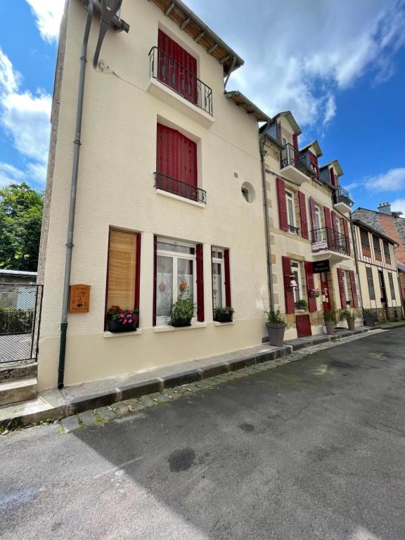 un bâtiment avec des fenêtres rouges à volets et des plantes en pot dans l'établissement B9 villa MASSIAS, à La Bourboule