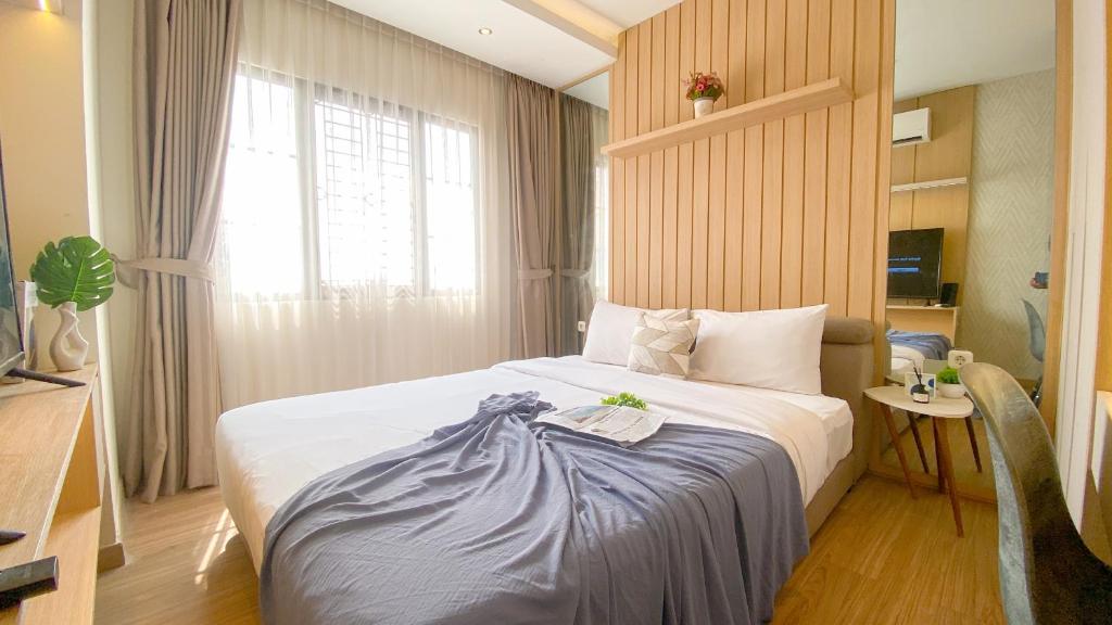 a hotel room with a bed and a window at Modern Look 2BR at Puri Garden Apartment By Travelio in Jakarta