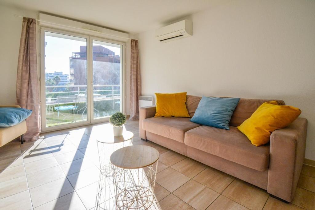 un salon avec un canapé et une grande fenêtre dans l'établissement Port Marianne avec terrasse et parking gratuit, à Montpellier